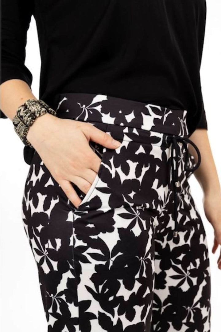 Pantalon fluide à imprimé floral noir et blanc avec taille élastique et poches, porté avec un haut noir.