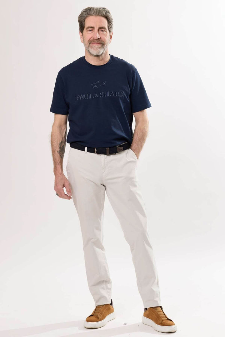 Homme portant un pantalon jambe droite beige et un t-shirt bleu marine, style décontracté et raffiné.