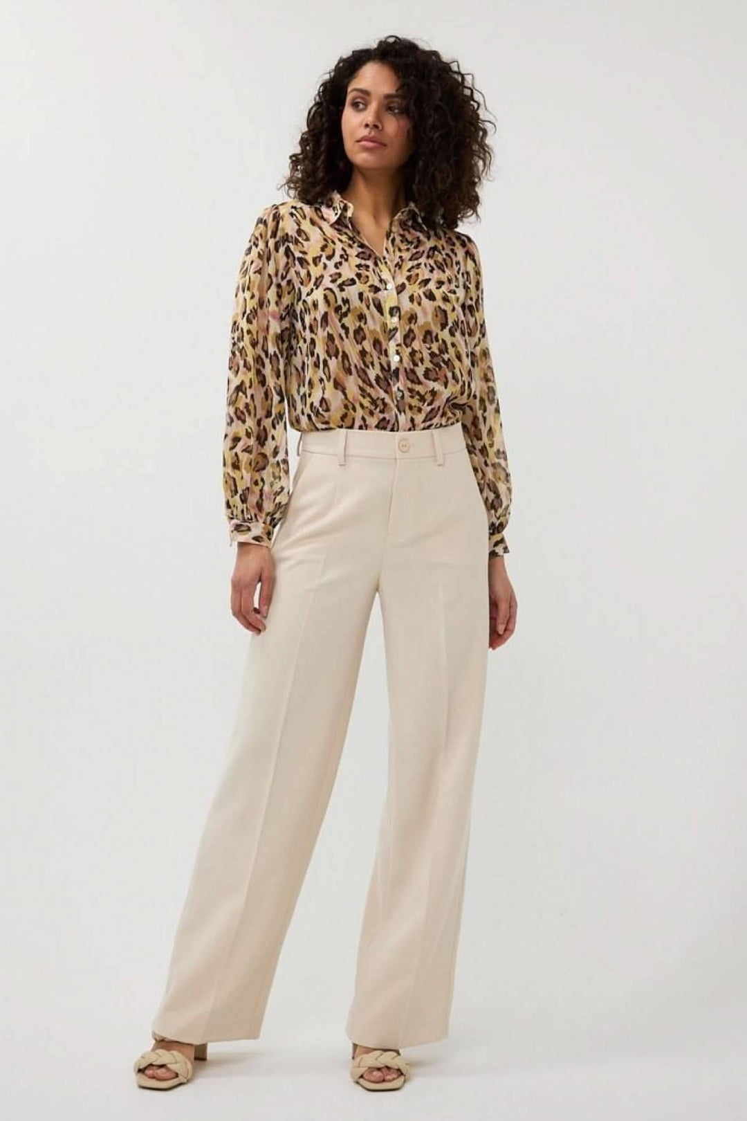Pantalon à jambe large beige avec chemisier à motifs, taille haute et plis marqués pour un look professionnel.