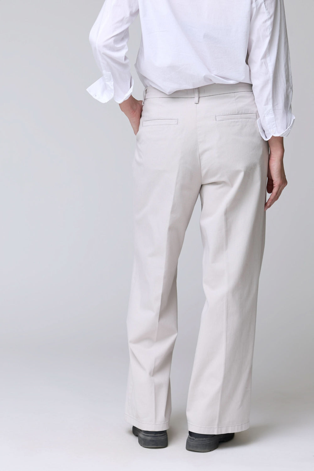 Homme portant un pantalon à jambe large blanc, élégant et confortable, avec ourlets nets et coupe fluide, décris moi le produit en français.