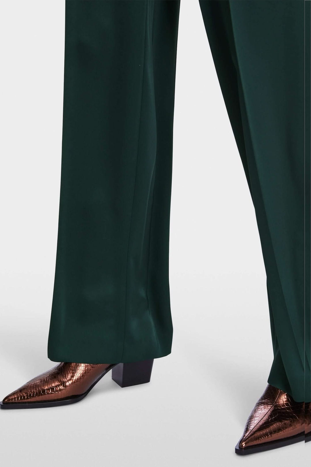 Pantalon à jambe large vert avec des chaussures à talons brillantes en bronze.