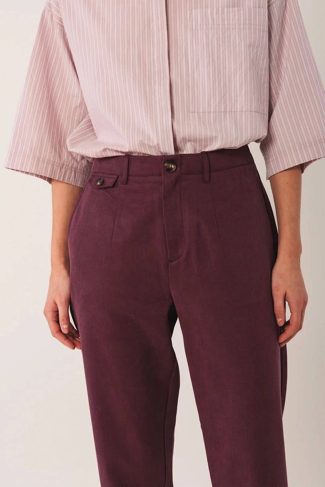 Pantalon à la coupe droite en tissu texturé, taille mi-haute, associé à une chemise oversize pour un style moderne et élégant.