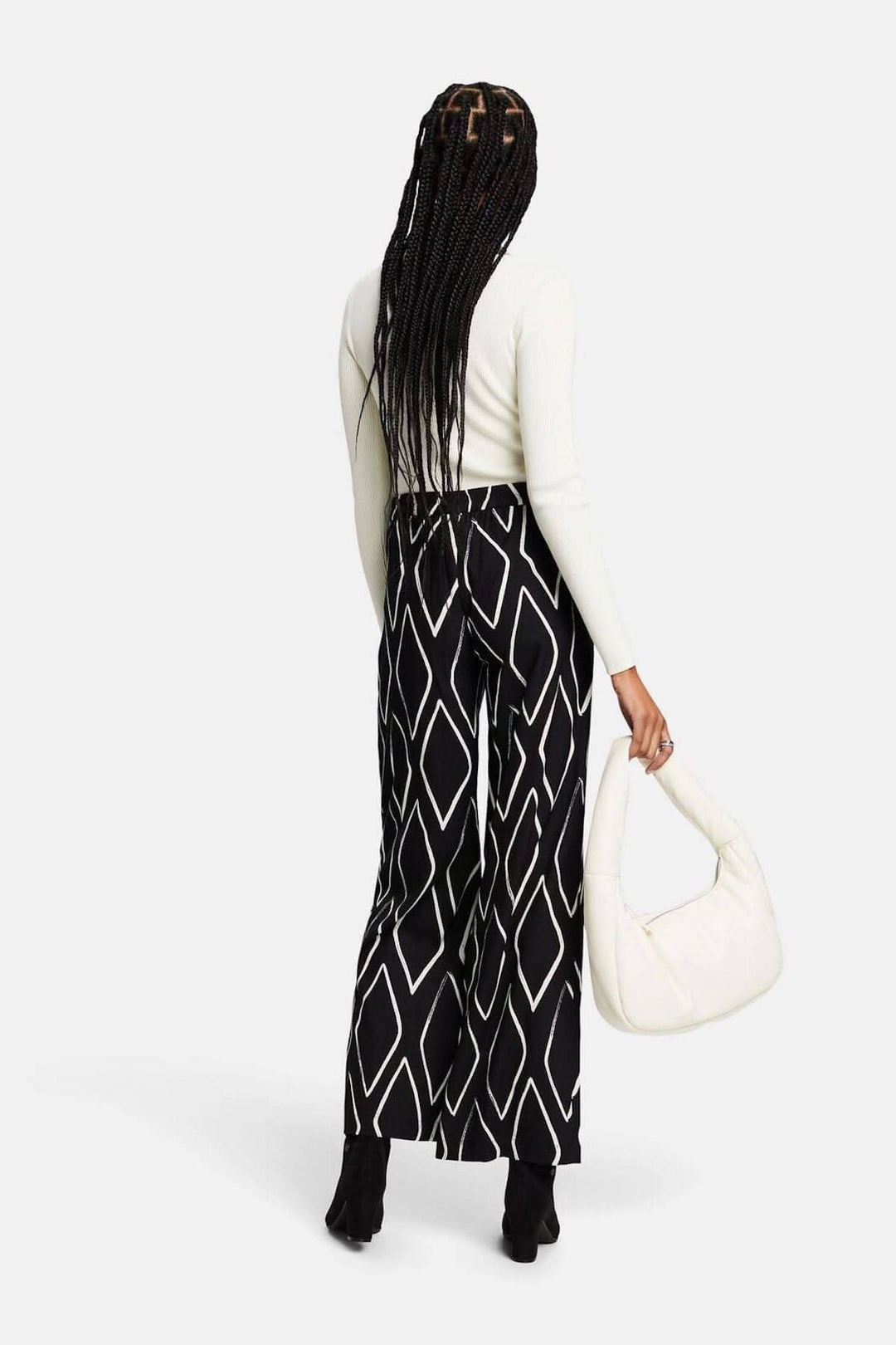 Pantalon large à enfiler imprimé losanges, porté avec un haut clair et un sac à main blanc.