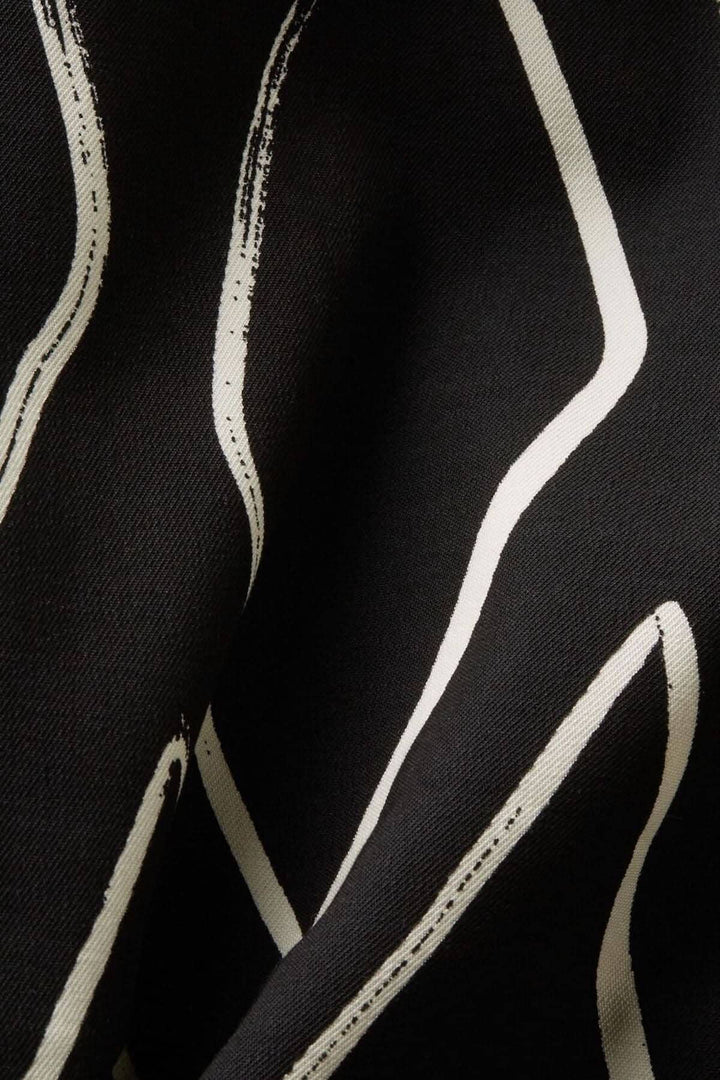Tissu noir avec motifs stylisés en blanc, texture douce et élégante pour un pantalon large imprimé.