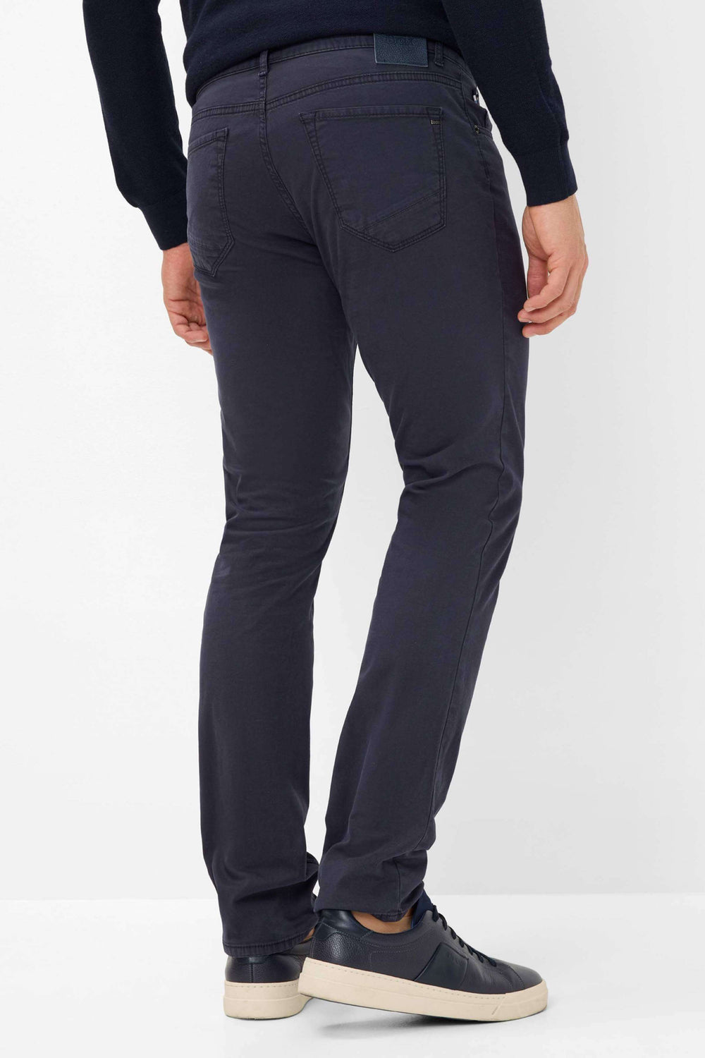 Pantalon marathon slim fit pour homme, détails en similicuir et clous, porté avec des baskets pour un look tendance.