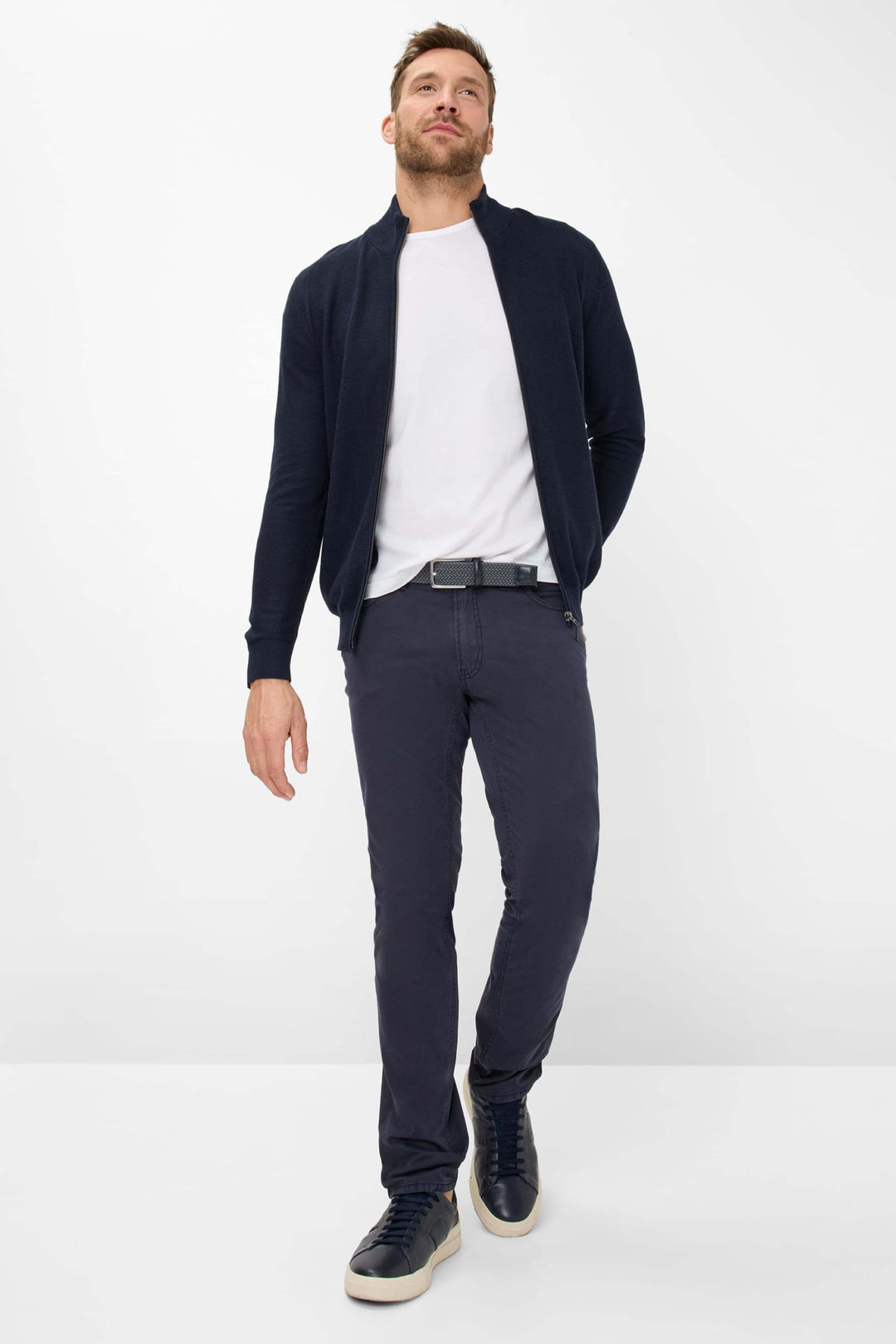 Homme portant un pantalon marathon slim et une veste sombre, avec des baskets, pour un look moderne et élégant.