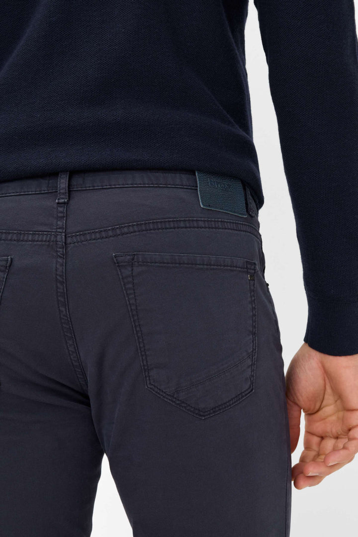 Pantalon homme style Chuck noir avec finitions en similicuir et coupe slim, porté avec un pull élégante.