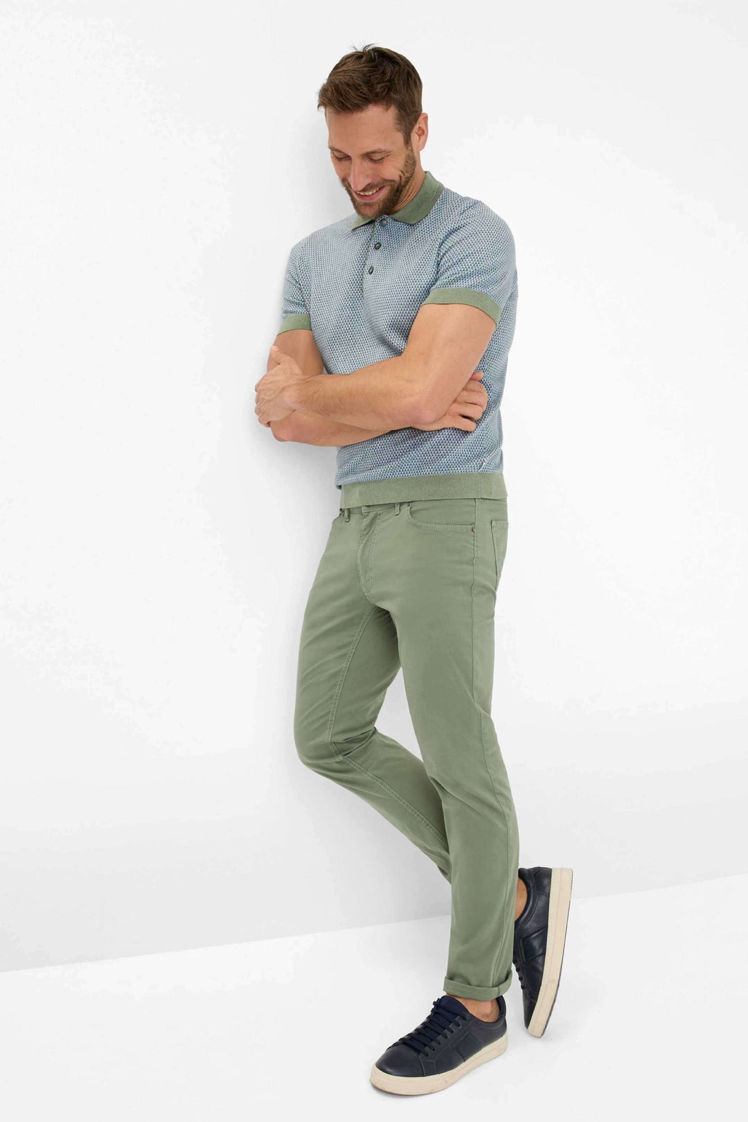 Homme élégant portant un polo bleu et un pantalon marathon vert, style moderne avec baskets confortables.