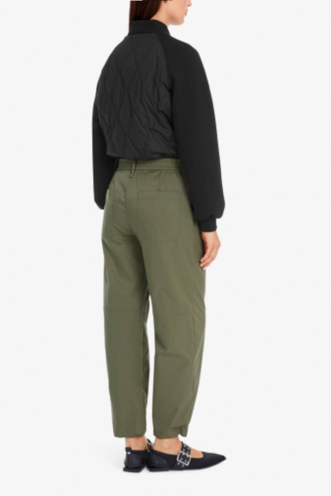 Femme vue de dos portant un pantalon style aviateur vert avec un bomber noir et des chaussures élégantes.