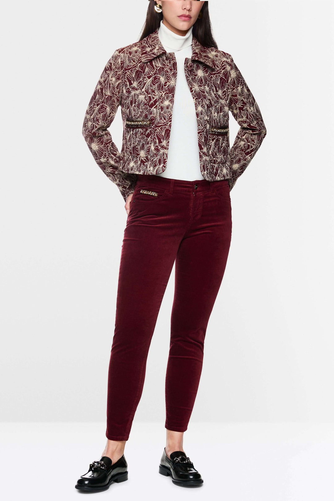 Femme portant un pantalon taille basse en velours rouge avec une veste à motif, style chic et moderne.