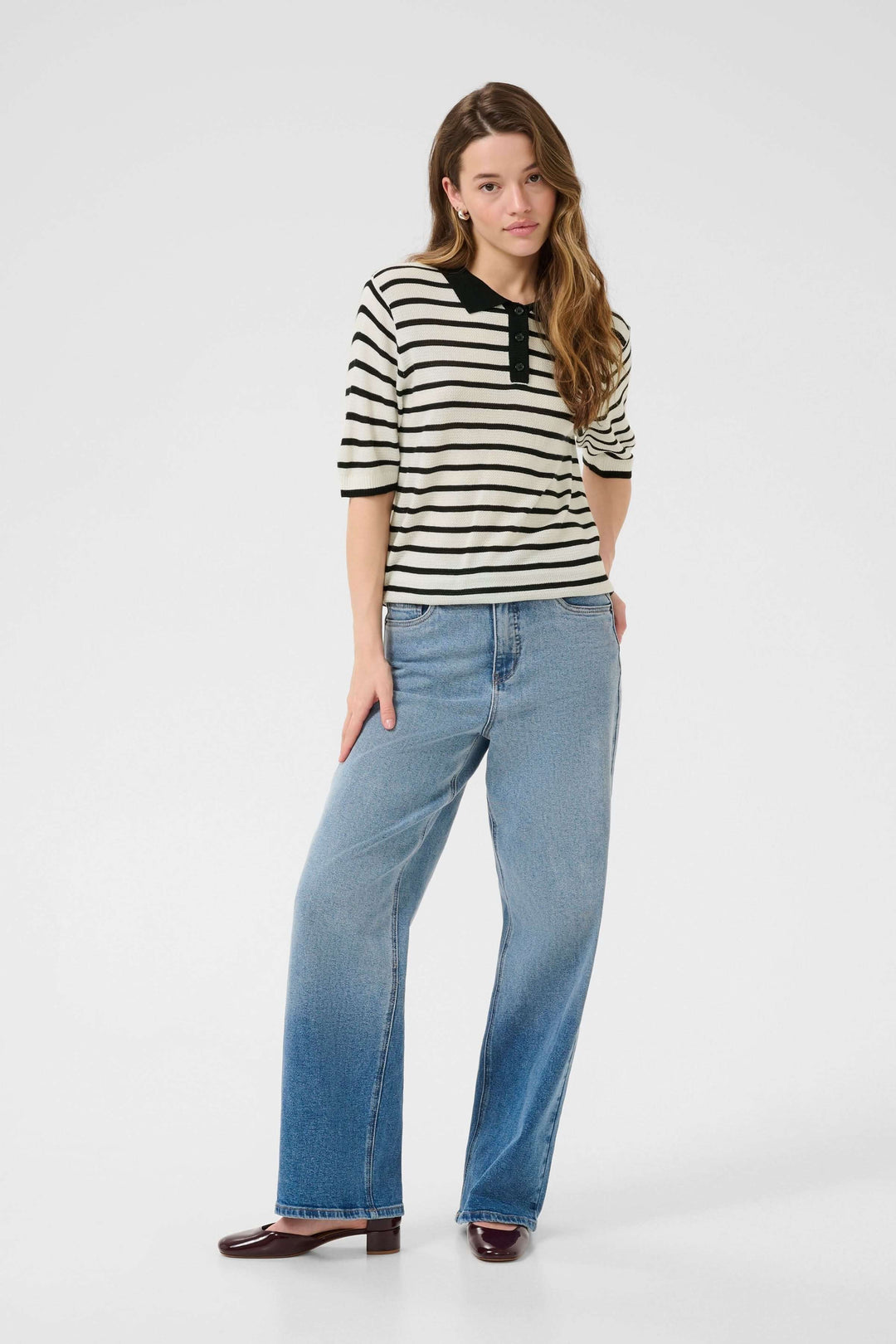 Femme portant un polo rayé rétro-chic avec un col contrastant, associé à un jean ample.