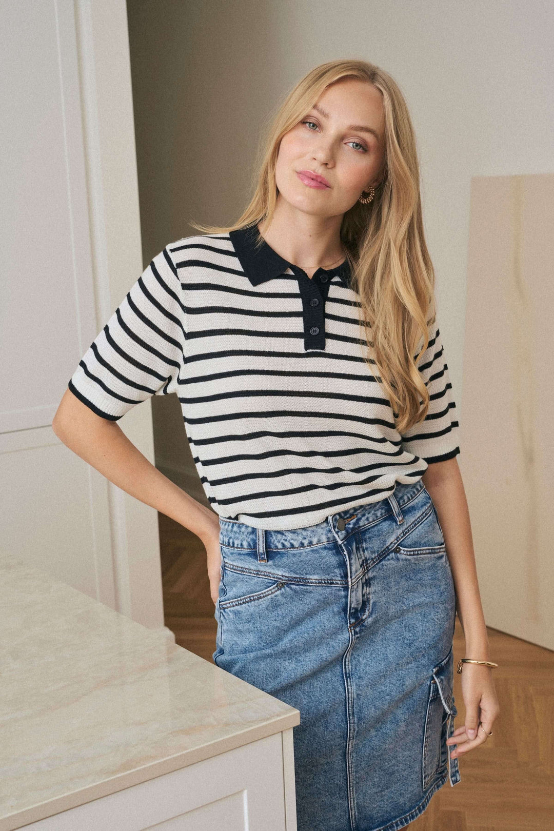 Polo Amalia à rayures légères, coupe moderne, col contrastant, porté avec une jupe stylée.