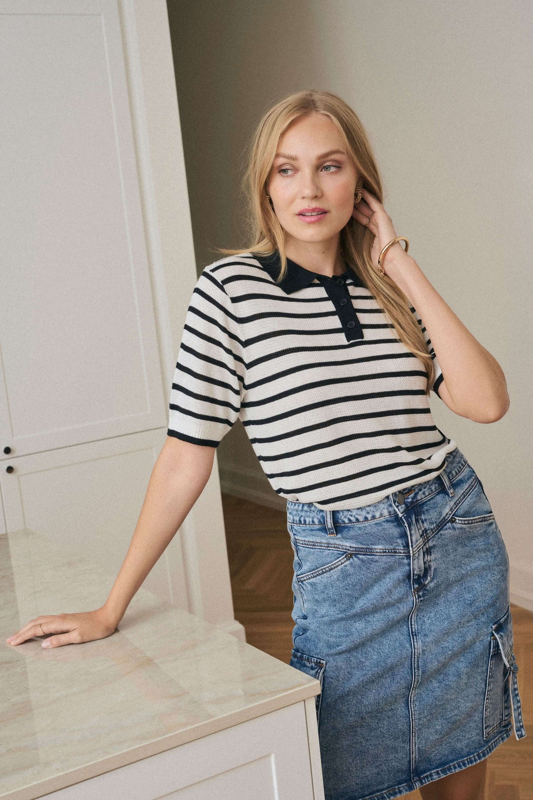 Polo Amalia rayé au style rétro-chic, porté avec une jupe en denim, pour un look casual et féminin.