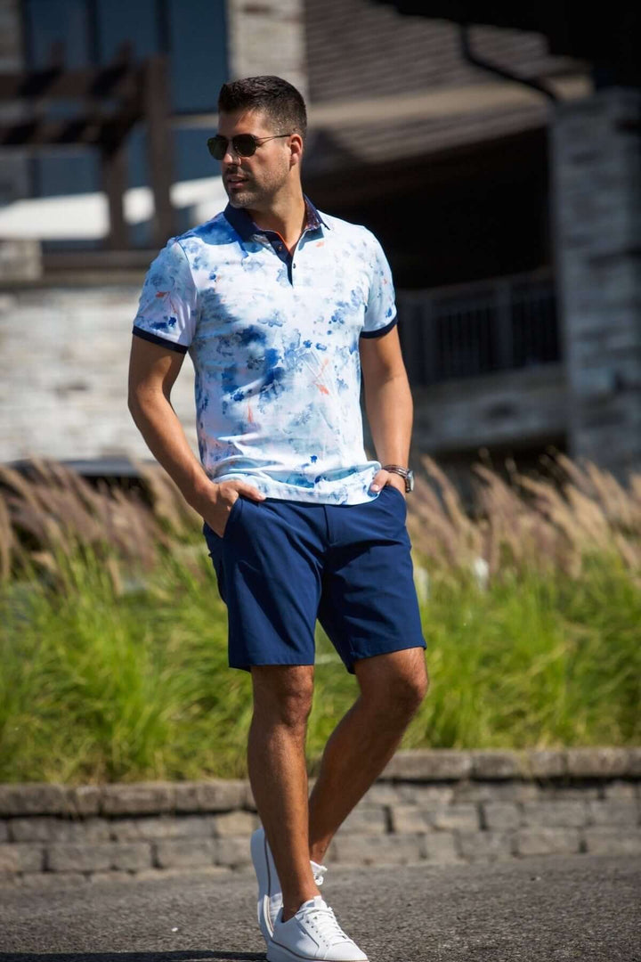 Homme portant un polo contrastant à motifs bleus avec un short, style décontracté estival.
