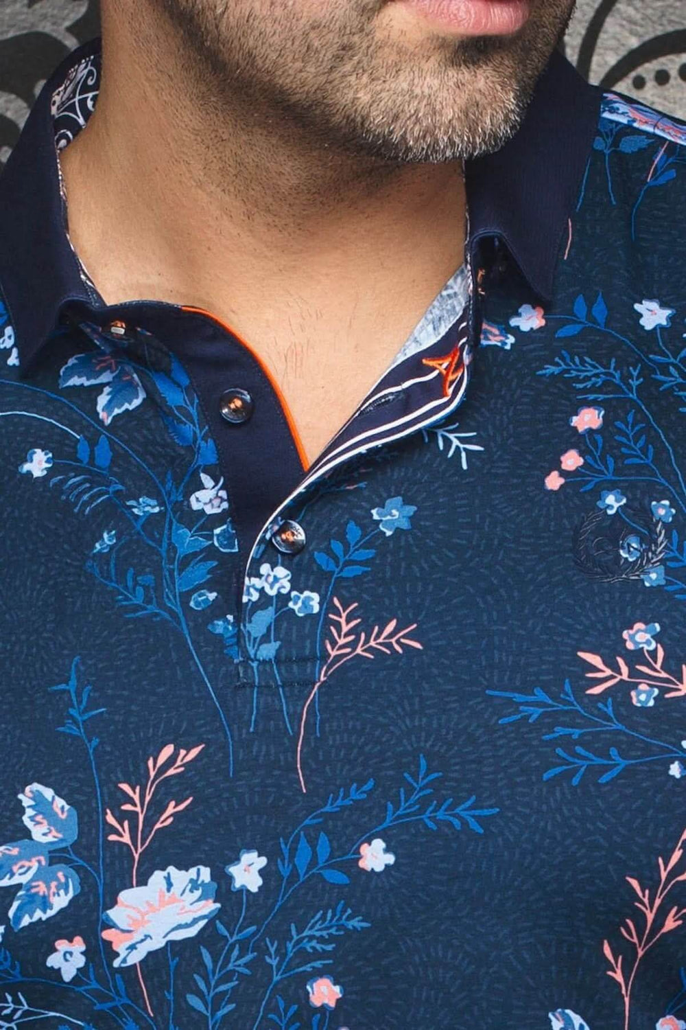 Polo fleuri pour homme sur fond marine, col structuré et imprimé floral charmant.