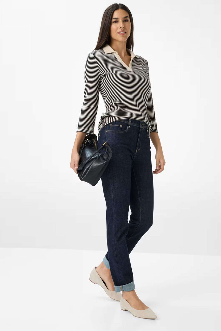 Femme portant le polo à rayures et jeans sombres, look chic et moderne, avec sac noir et chaussures claires.