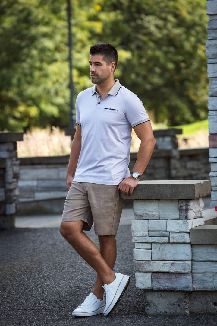 Homme portant un polo Mayberry à micro-motif, shorts beiges et chaussures blanches dans un cadre extérieur.