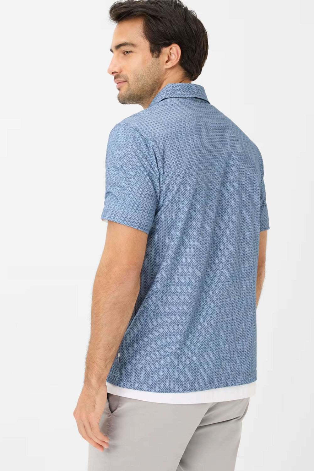 Homme portant un polo à manches courtes bleu avec motif géométrique, vue arrière, style décontracté chic.