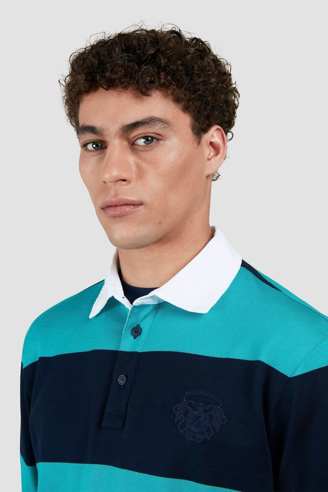 Homme portant un polo rugby à rayures turquoise et bleu avec col blanc, look décontracté et sportif.
