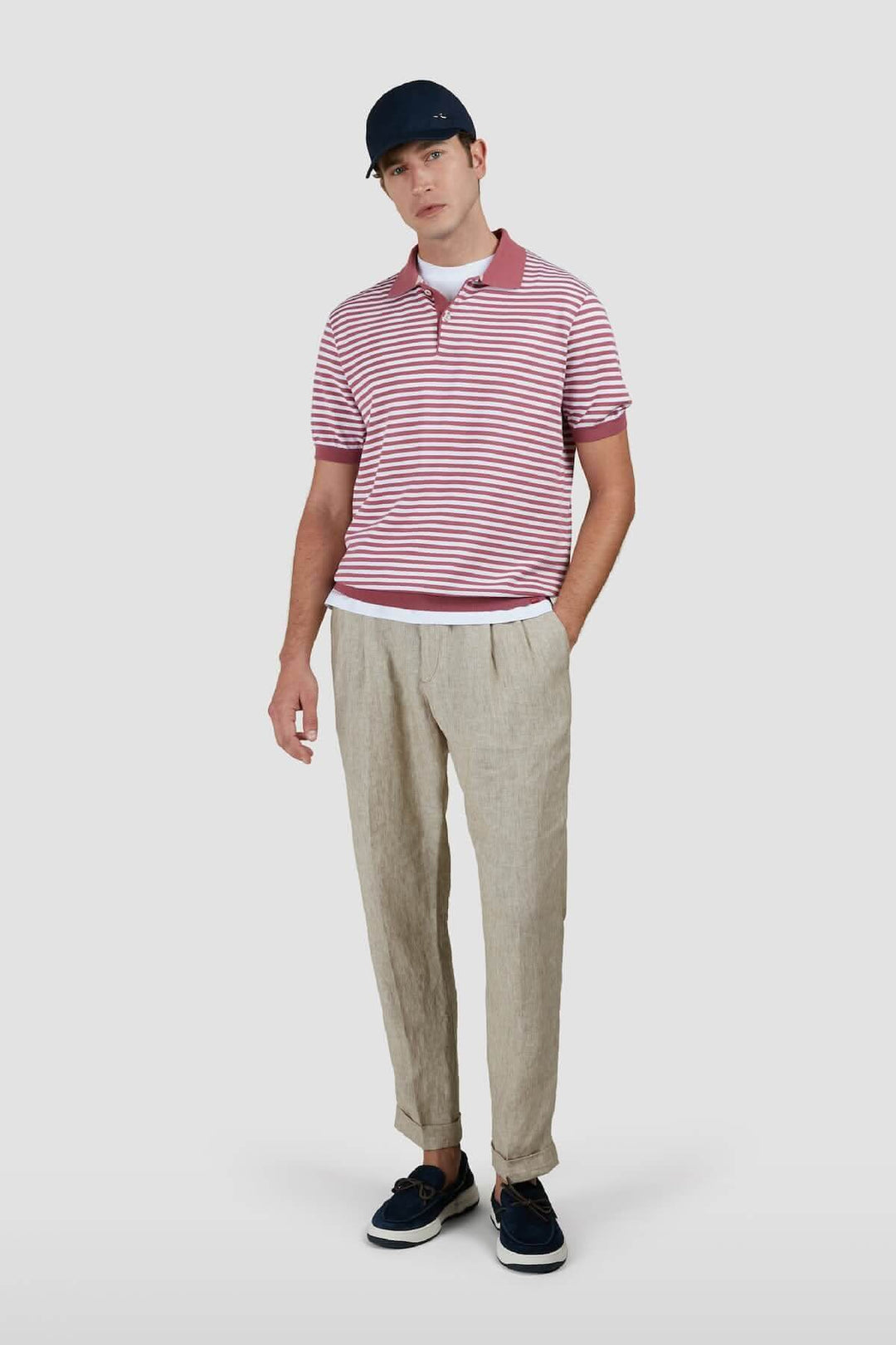 Homme portant un polo à rayures bicolores avec col contrastant et pantalon en lin, look décontracté.