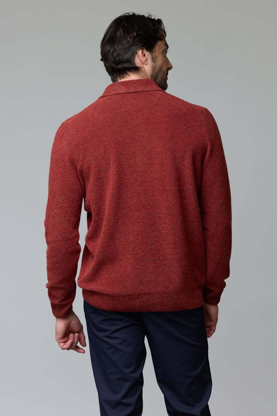 Homme portant un polo en laine mérinos rouge, coupe ajustée, de dos, montrant la finesse du tissu et le col classique à trois boutons.