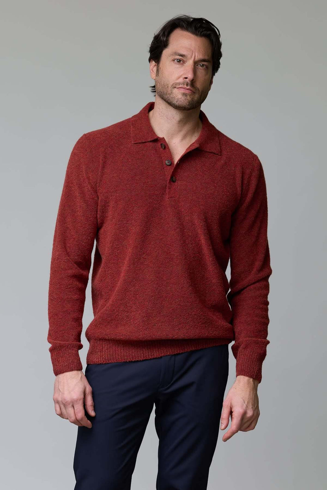 Homme portant un polo en laine mérinos rouge avec col classique à trois boutons, coupe ajustée et élégante. Parfait pour un look décontracté.