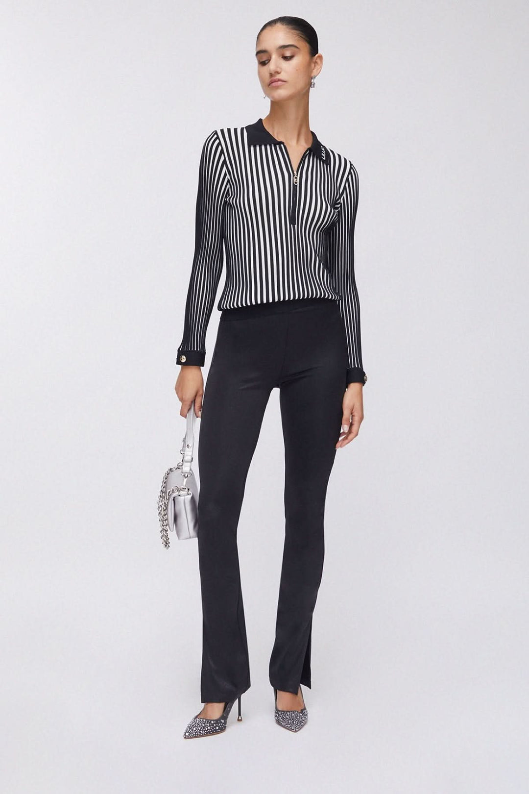 Femme portant un polo en maille côtelée à demi-glissière avec pantalons noirs élégants, style contemporain et confortable.
