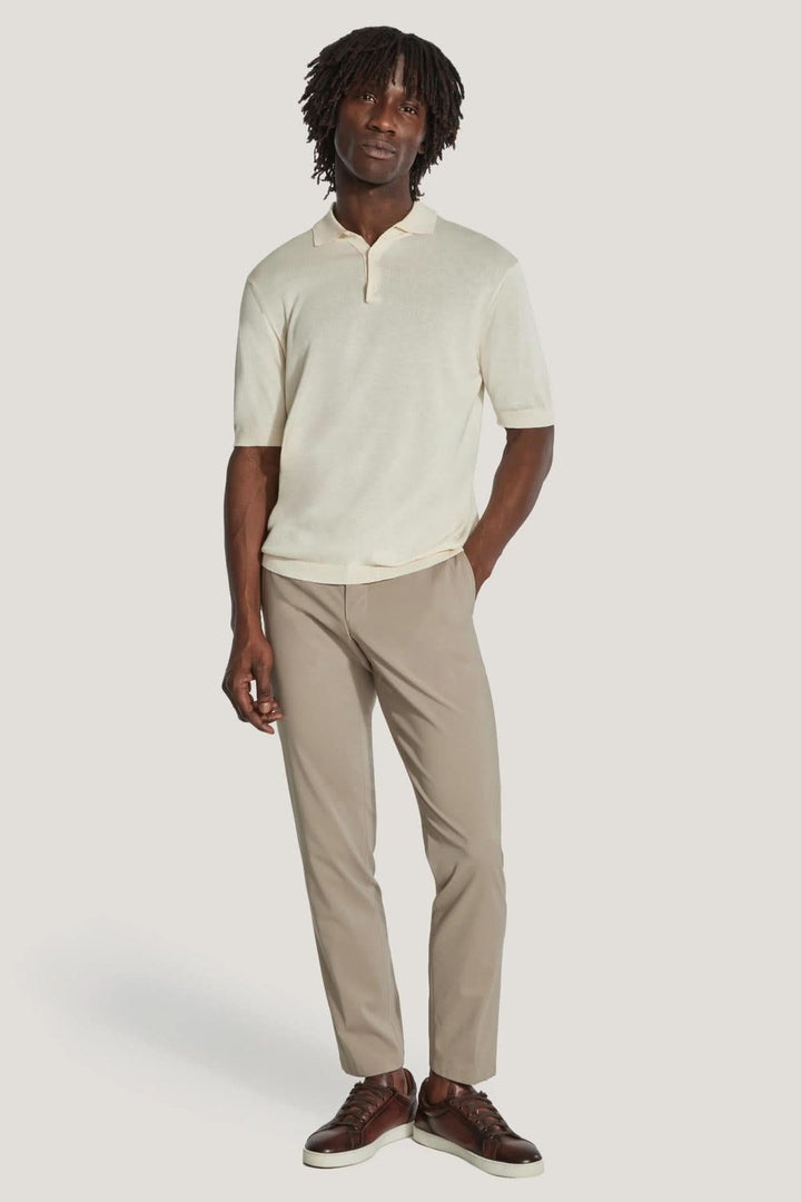 Homme portant un polo en tricot beige avec pantalon clair, style décontracté et élégant.