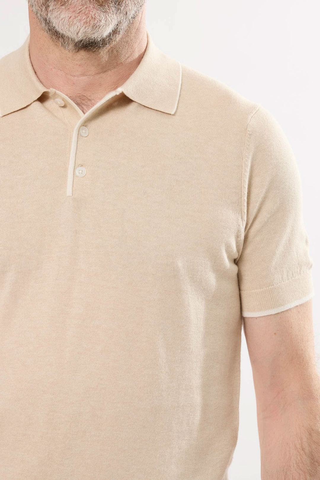 Polo en tricot fin beige pour homme, style sobre et raffiné avec col classique et manches courtes.