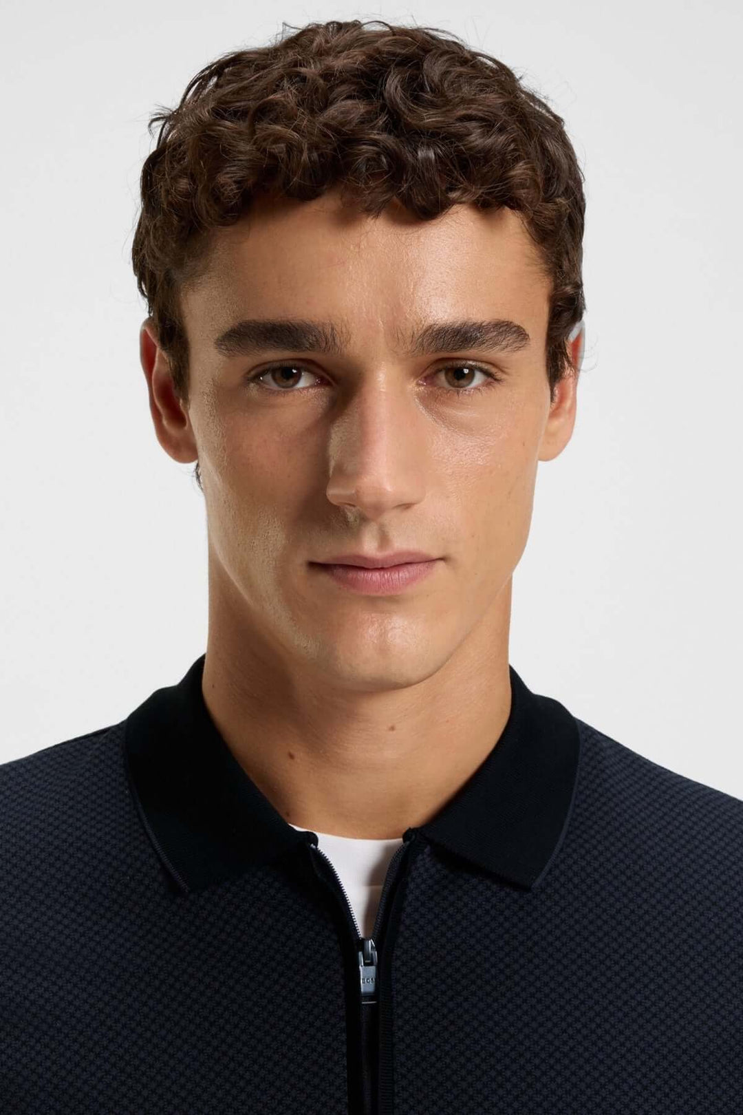 Homme portant un polo à manches longues avec fermeture éclair, style élégant et contemporain avec col contrastant.