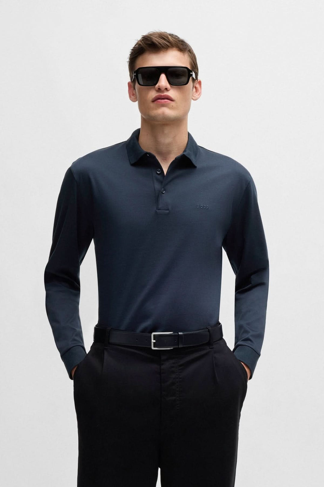 Homme portant un polo manches longues en coton noir BOSS avec lunettes de soleil et pantalon noir.