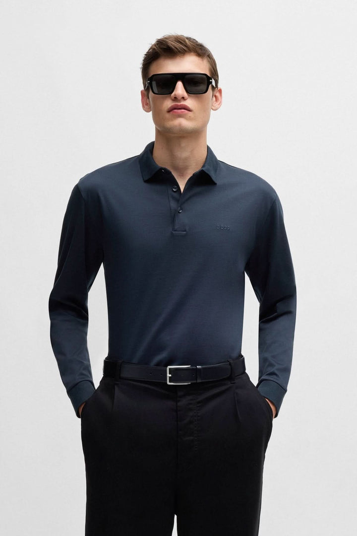 Homme portant un polo manches longues en coton noir BOSS avec lunettes de soleil et pantalon noir.