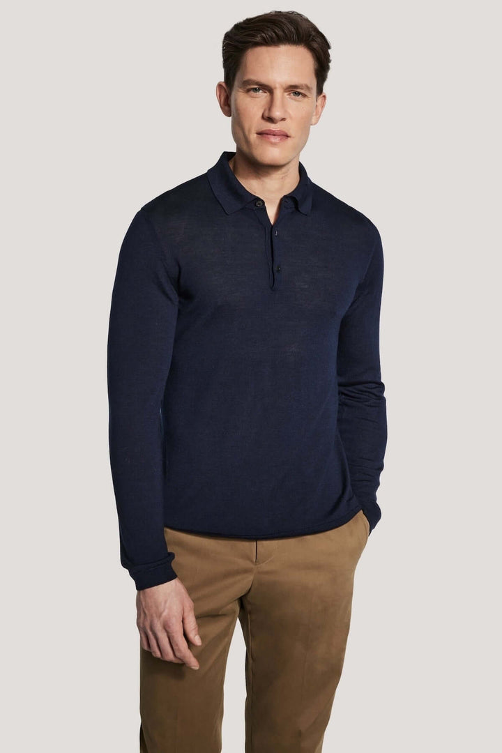 Homme portant un polo manches longues en laine mérinos et soie, bleu foncé, style moderne et élégant.