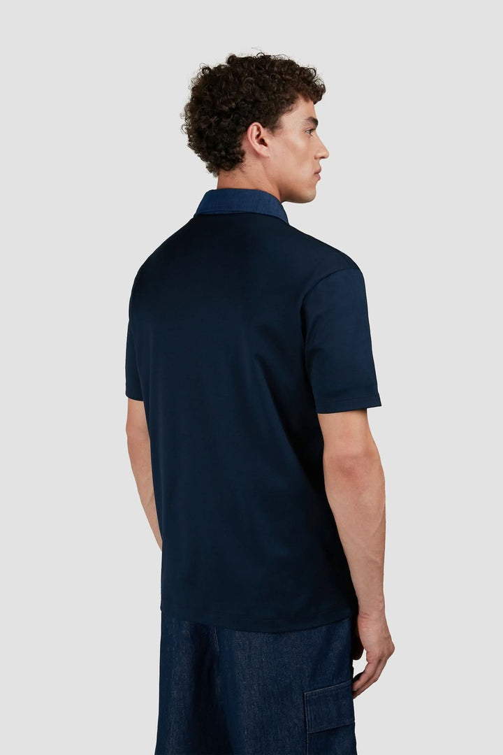 Homme portant un polo marine en coton avec col contrastant en denim, vue arrière, style décontracté et contemporain.