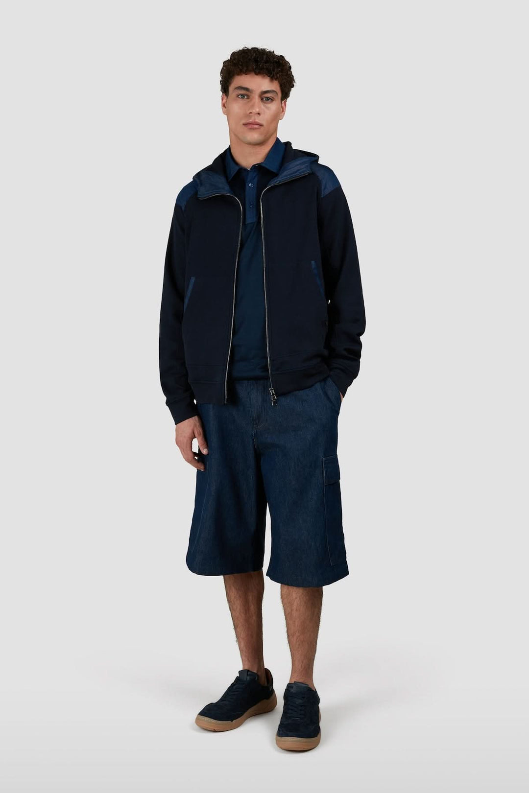 Homme portant un polo en coton marine avec col contrastant et un short en denim, style décontracté.