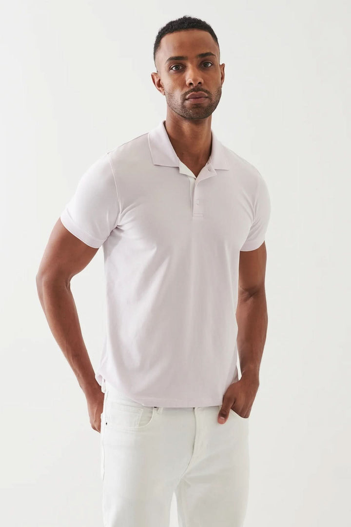 Homme portant un polo épuré à manches courtes de couleur lilas, style élégant et ajusté.