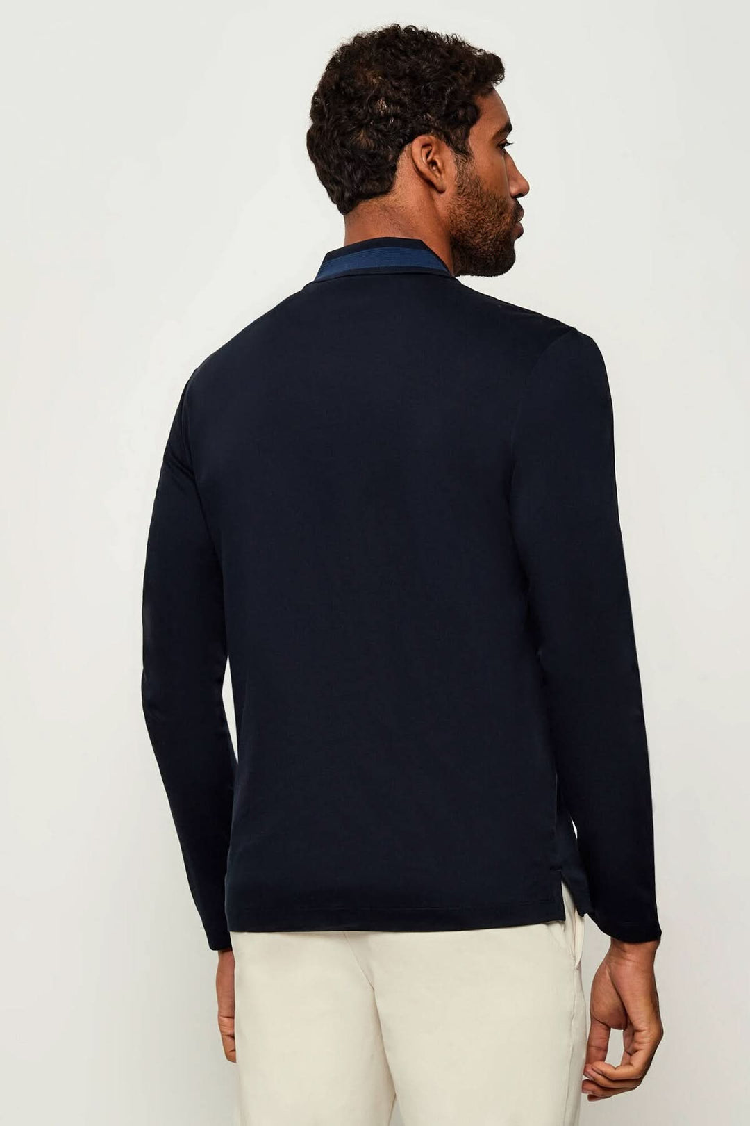 Homme portant un Polo slim fit à manches longues BOSS avec col côtelé, vu de dos, couleur bleu marine, style chic et décontracté.