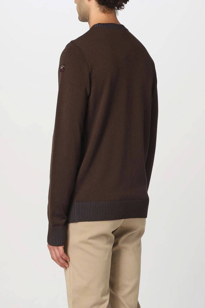 Pull en laine marron avec col et détails contrastants en bleu, porté dans un style chic décontracté.