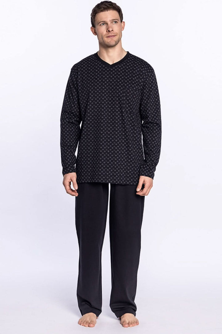 Homme portant un pyjama long en coton, t-shirt noir à motifs et pantalon uni, style minimaliste et confortable.