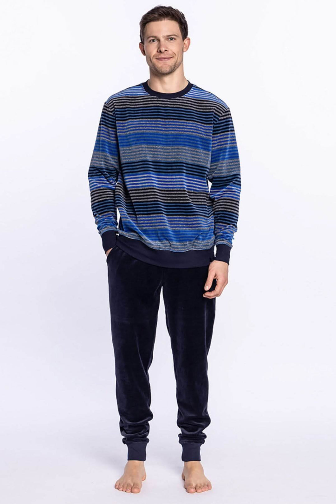 Homme portant un pyjama long en velours, tee-shirt rayé bleu et pantalon uni, idéal pour l'hiver.