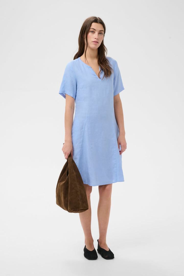 Robe Aminasa bleue à encolure en V, manches courtes et coupe fluide, idéale pour une allure élégante et naturelle. Poches latérales discrètes.