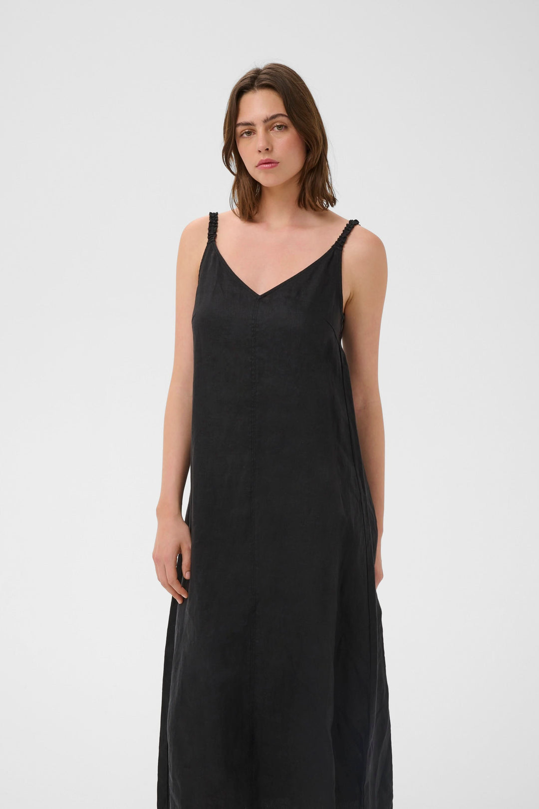 Femme portant la Robe Elinor midi fluide à bretelles fines, encolure en V, coupe ample, longueur midi, tissu léger et respirant.