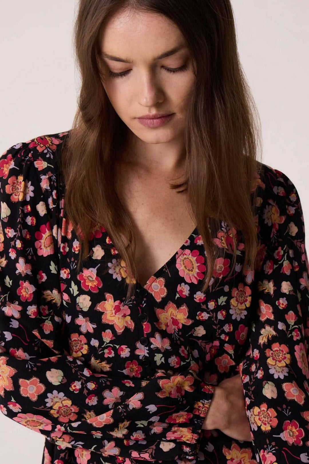 Femme portant la robe Eliota en fleurs avec décolleté V et manches longues, parfaite pour l&