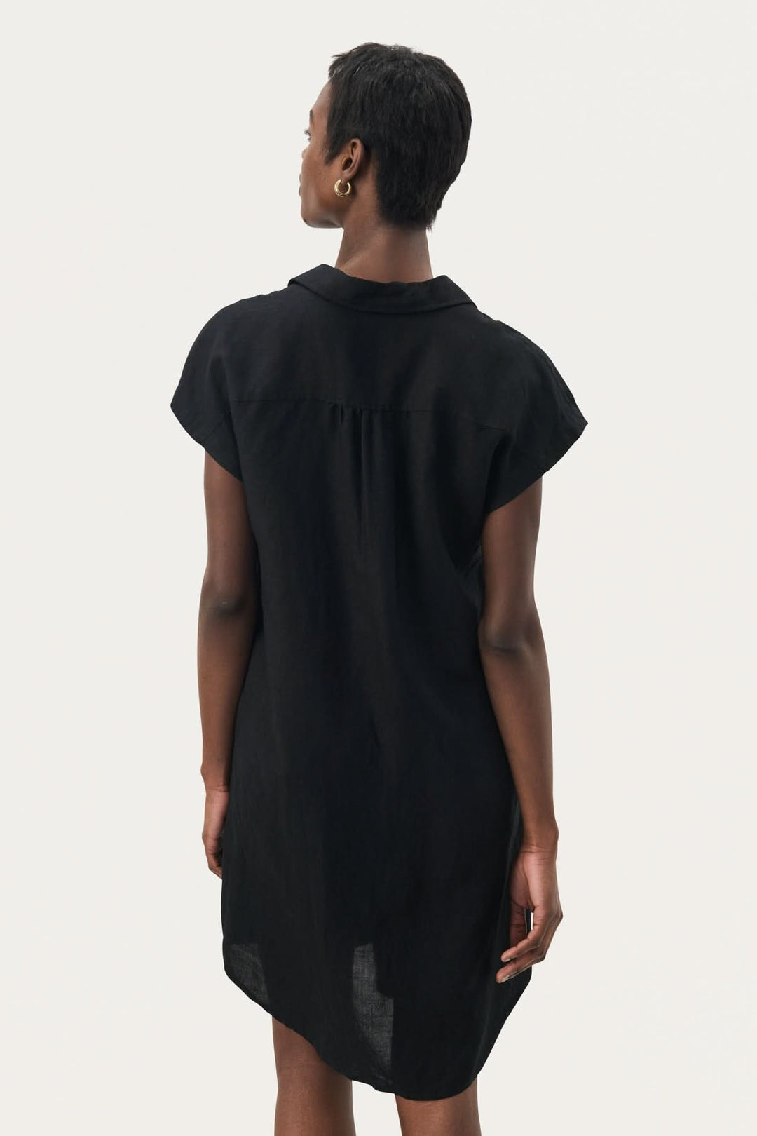 Femme portant la robe décontractée Ellena, vue de dos, en noir, avec col chemise et manches courtes.