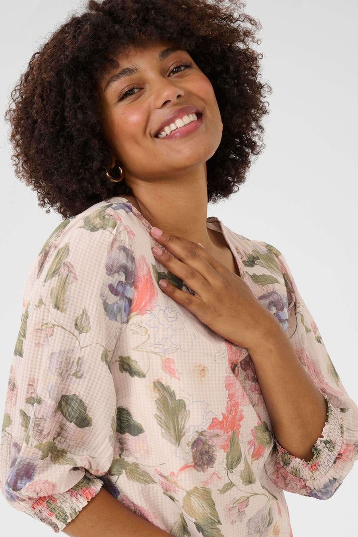 Femme souriante portant une robe fluide à imprimé floral, mettant en avant l'élégance bohème.