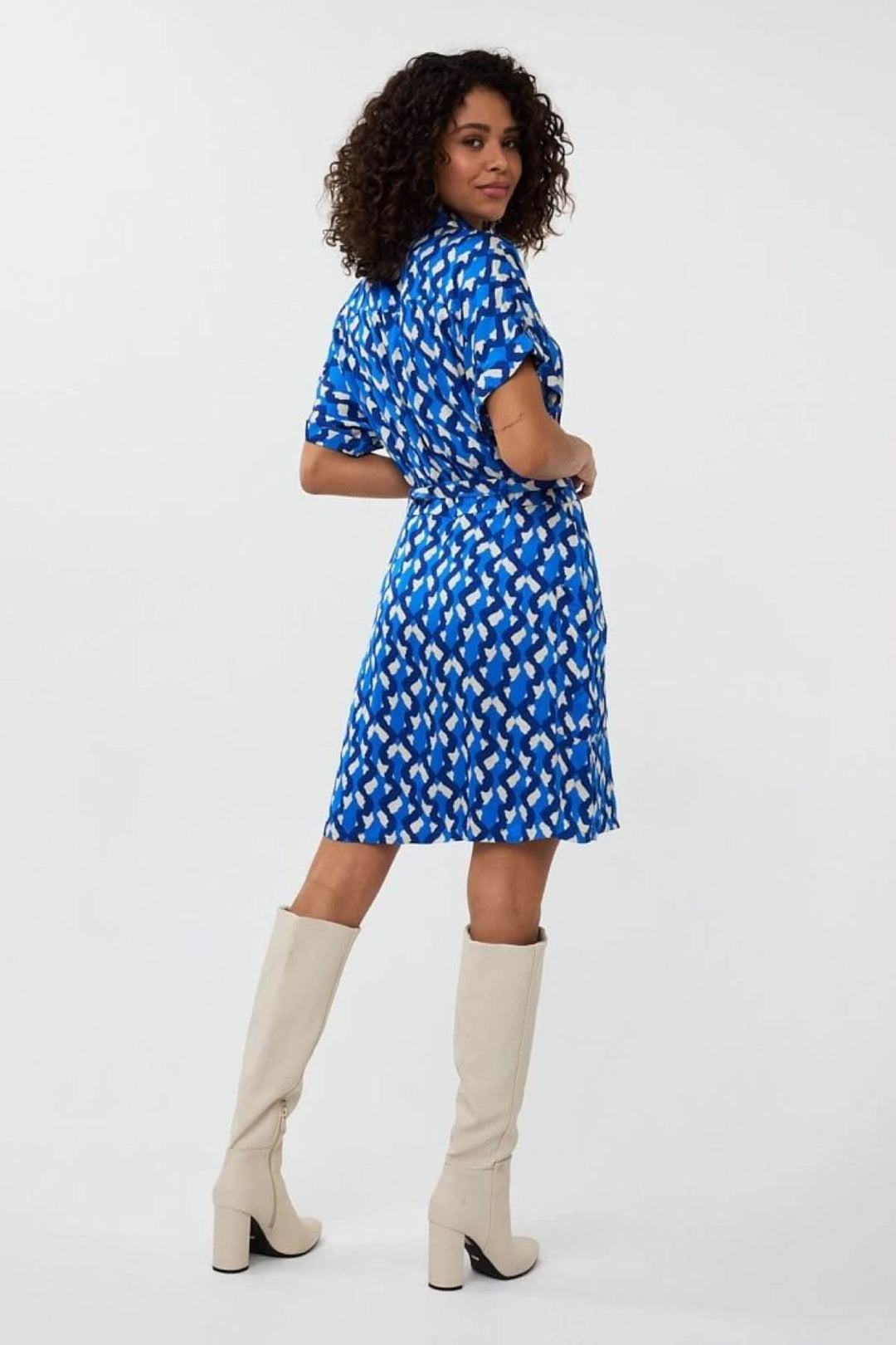 Robe Utopia à imprimé abstrait, en tissu satiné, portée par un modèle avec des bottes blanches.