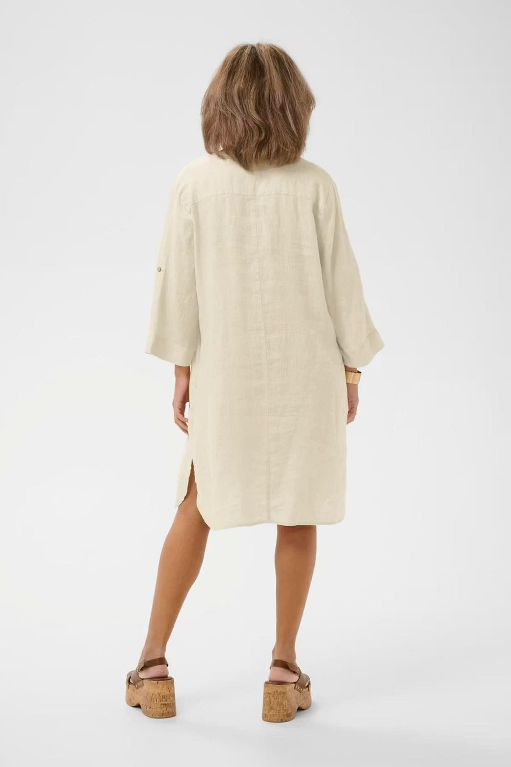 Vue arrière de la robe chemise en lin beige avec coupe ample et manches retroussables, élégant et décontracté, sur mannequin.