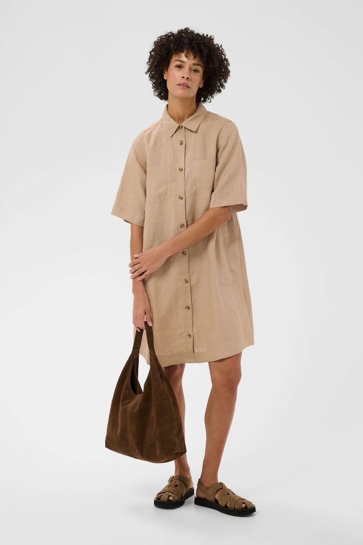 Femme portant une robe chemise en lin Sardiae, silhouette droite avec fermeture boutonnée, style décontracté et soigné.