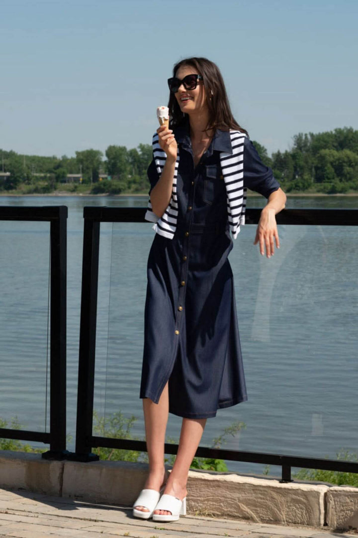 Femme en robe chemisier aspect denim, lunettes de soleil, dégustant une glace près d'un plan d'eau.