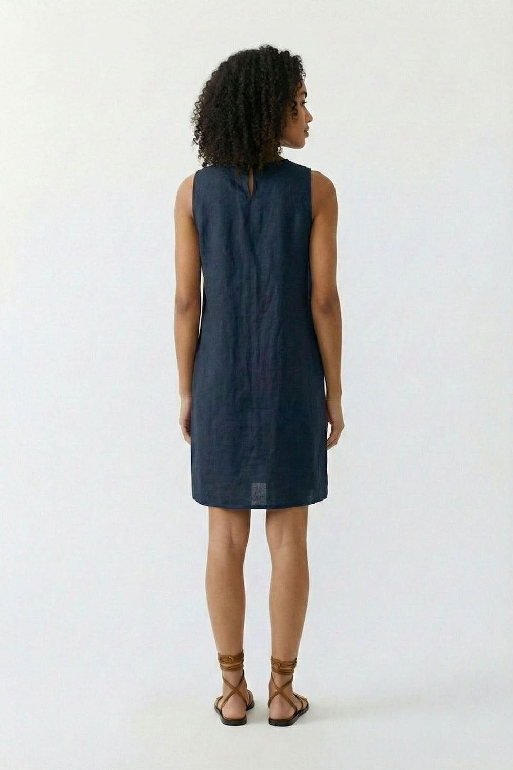 Robe coupe fluide intemporelle en tissu léger vue de dos, femme debout, dos à la caméra, style élégant et naturel.